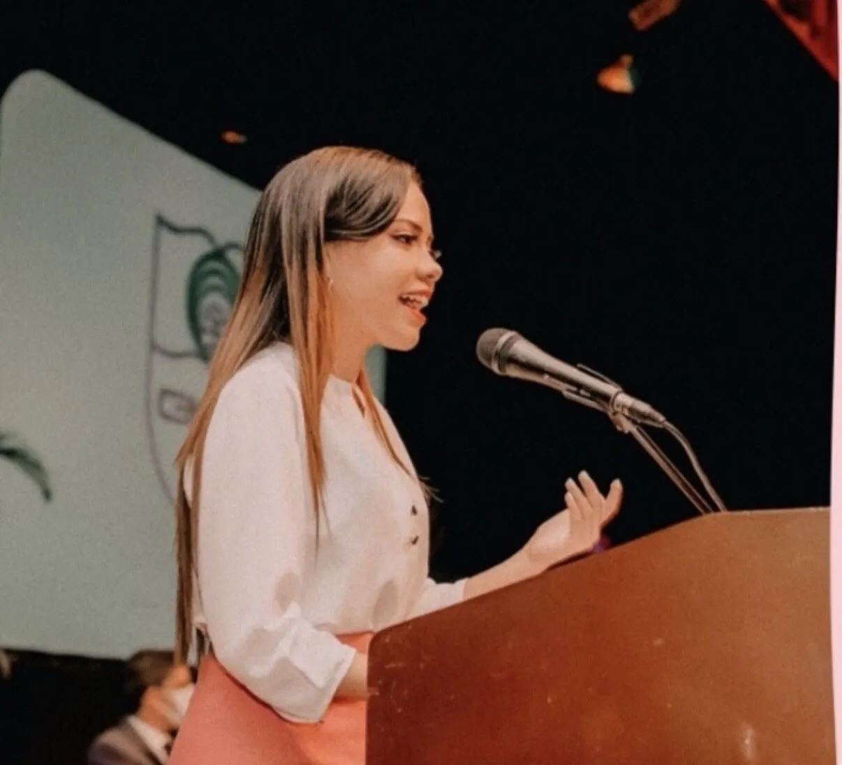 Laura Minyetty presentando un evento desde el atril
